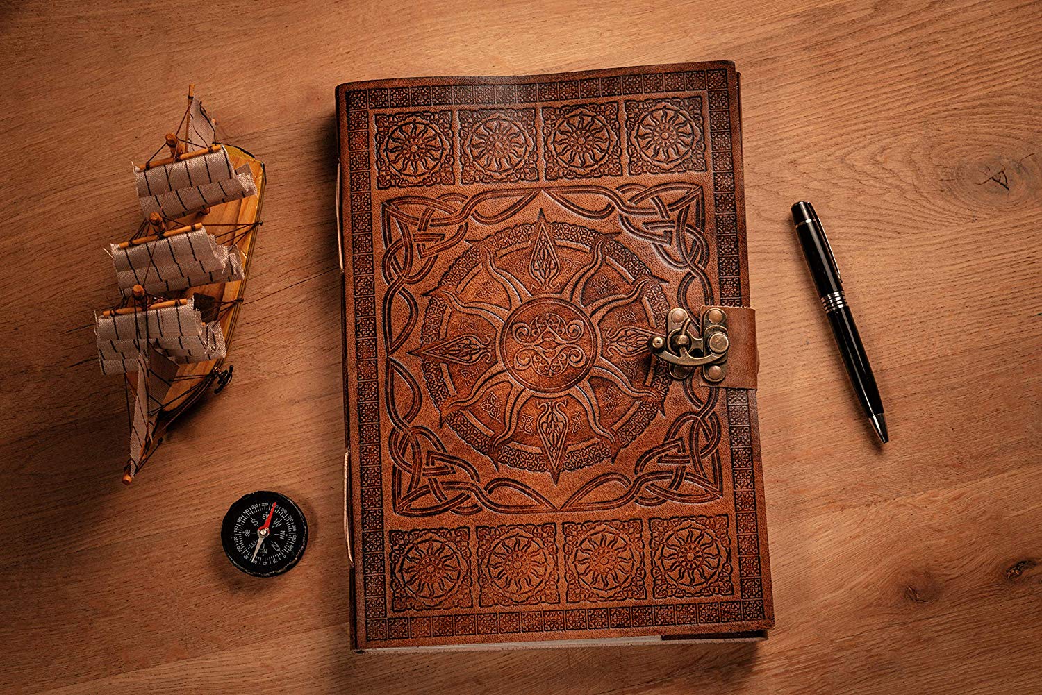 A4 tan leather journal on table next to pen, compass and model ship