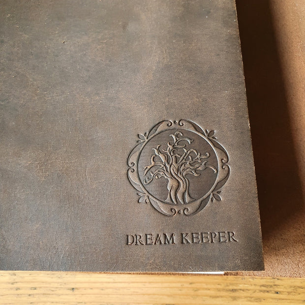 Close up of Tree of Life embossing on front cover of dark brown leather