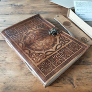A4 handmade leather journal on table next to leather embossed book mark and protective box