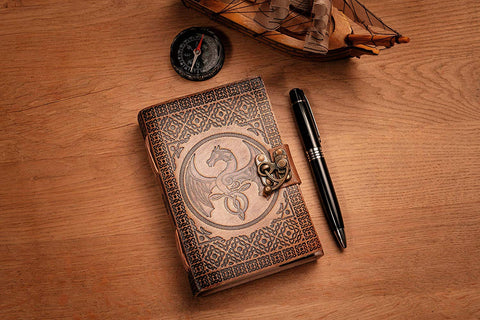 Small journal, leather handbound, placed on a table next to a pen, compass and model ship