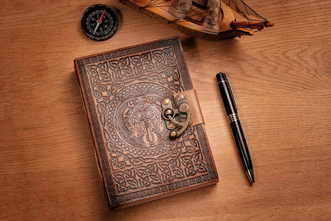 Celtic journal resting on table alongside pen, compass and model ship