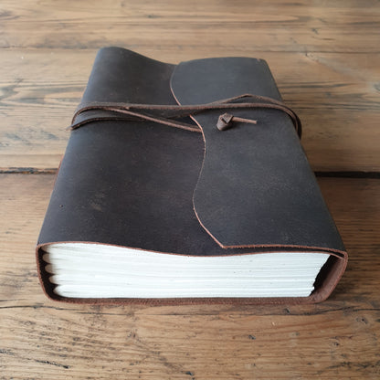 Vintage leather thick A5 journal with wrap around tie, showing edge of white paper